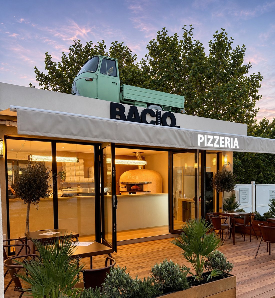 Façade de la pizzeria BACIO à Marseille, avec le triporteur en déco sur le toit et la terrasse éclairée